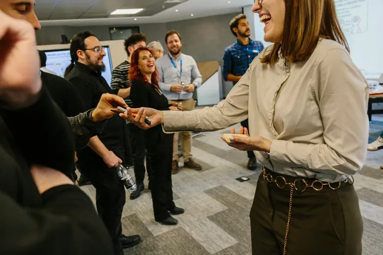 Participantes de un taller riendo mientras se pasan los plumones