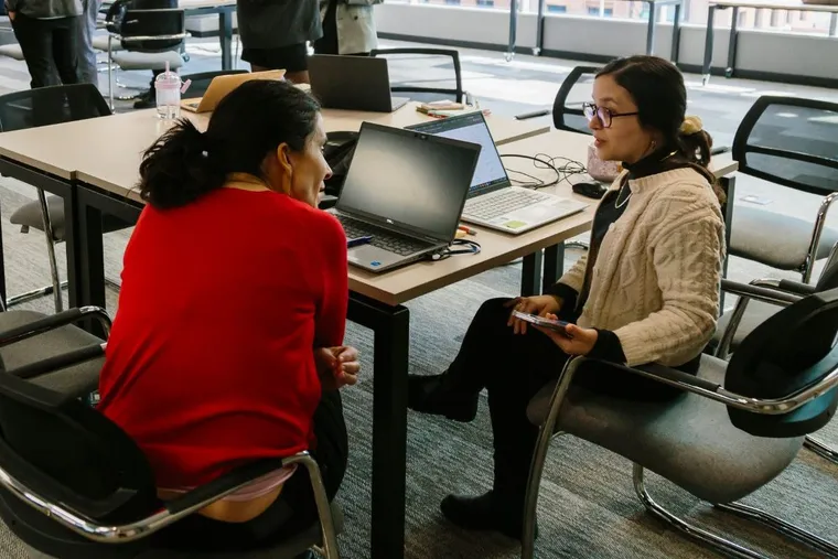 Dos integrantes de un equipo conversando frente a sus computadores